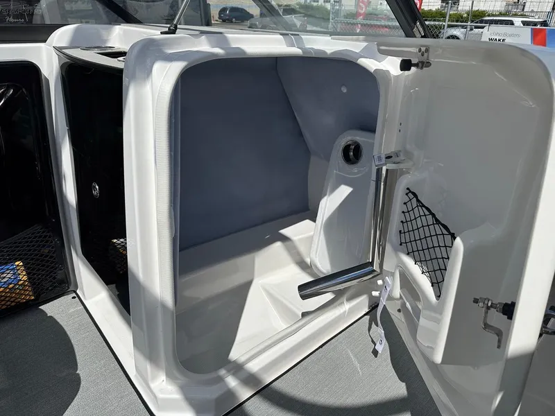 Slide: The Image of 2024 Yamaha AR250 jet boat interior storage compartment with open door and netted pocket. - 16