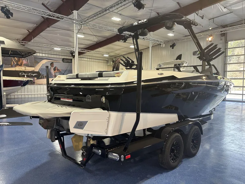Slide: The Image of 2025 Axis A225 boat on trailer in showroom, featuring sleek black and white design. - 4