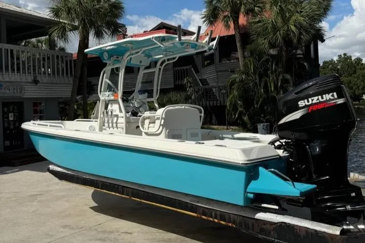 Slide: The Image of 2008 Everglades 243 CC boat with Suzuki engine, docked near tropical trees. - 1