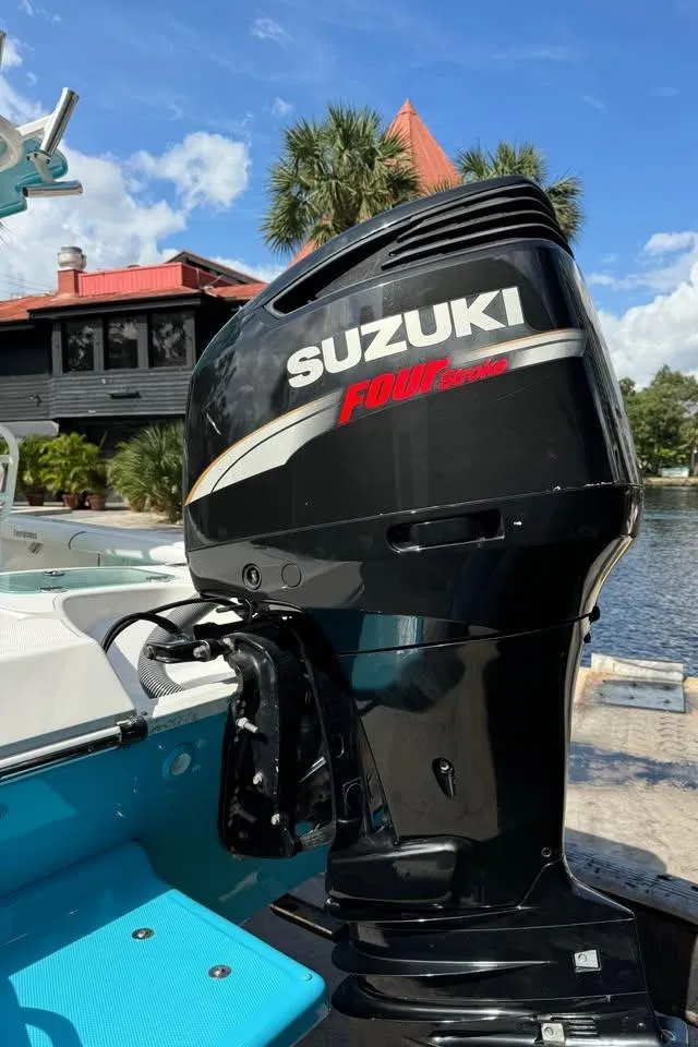 Slide: The Image of Suzuki outboard motor on 2008 Everglades 243 CC boat, docked by a scenic waterfront. - 2