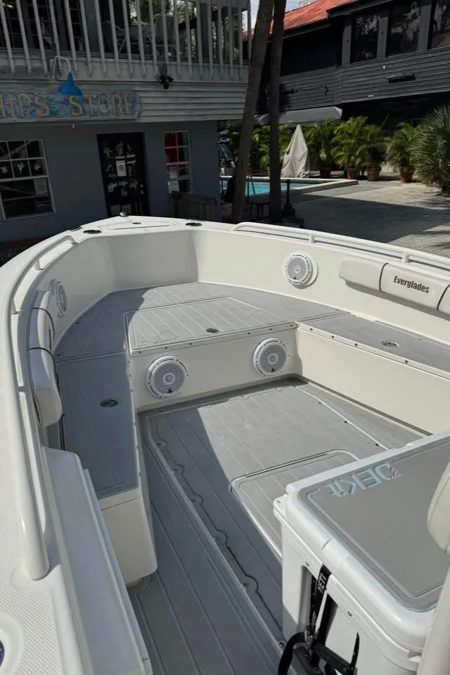 Slide: The Image of 2008 Everglades 243 CC boat with spacious deck and seating, docked near a building. - 3