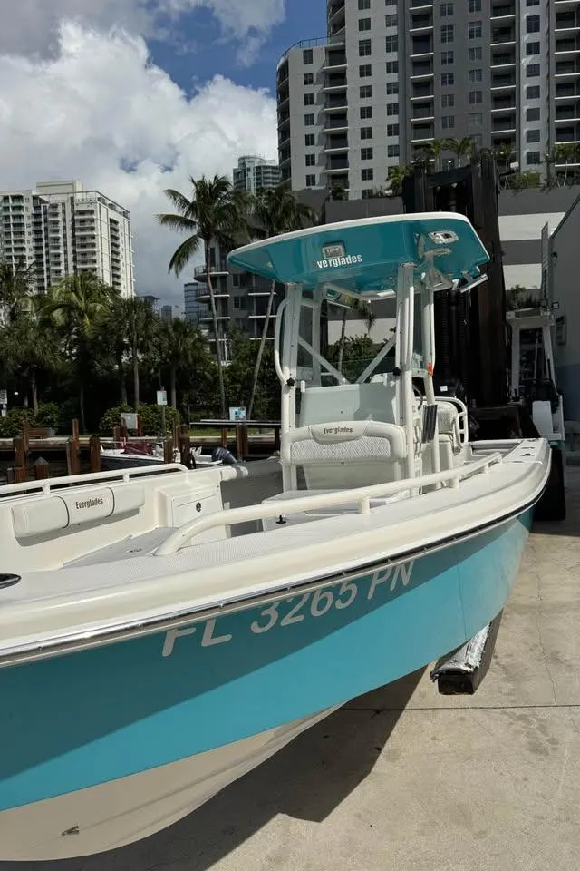 Slide: The Image of 2008 Everglades 243 CC boat docked, turquoise hull, urban background, clear sky. - 7