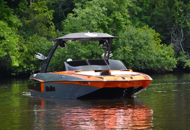 Slide: The Image of 2020 Malibu Wakesetter 22 MXZ boat on a calm lake, surrounded by lush greenery. - 11
