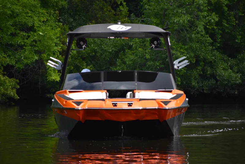 Slide: The Image of 2020 Malibu Wakesetter 22 MXZ boat on calm water, surrounded by lush greenery. - 12