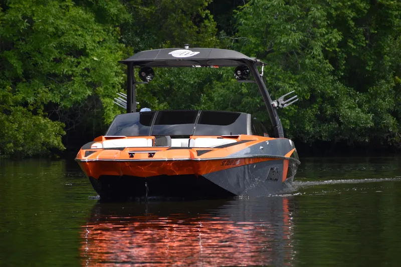 Slide: The Image of 2020 Malibu Wakesetter 22 MXZ boat on calm water, surrounded by lush greenery. - 13