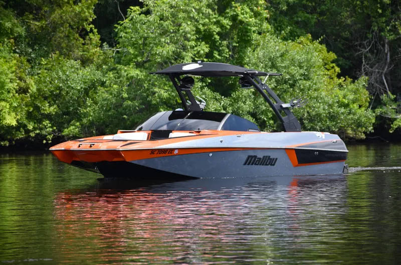 Slide: The Image of 2020 Malibu Wakesetter 22 MXZ boat on a calm lake with lush greenery. - 15