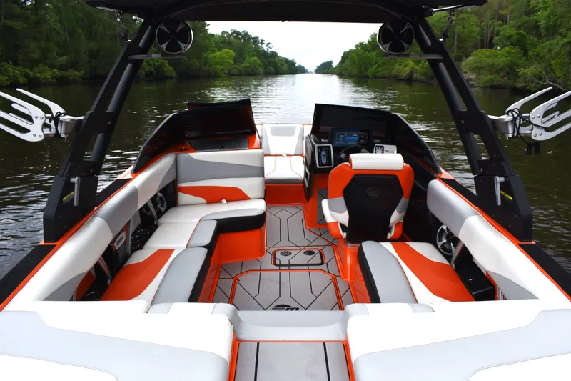 Slide: The Image of 2020 Malibu Wakesetter 22 MXZ boat interior with orange and white seating on a river. - 16