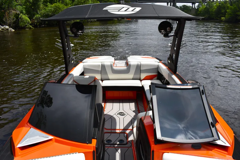 Slide: The Image of 2020 Malibu Wakesetter 22 MXZ boat with sleek orange and white design on a river. - 18
