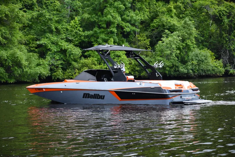 Slide: The Image of 2020 Malibu Wakesetter 22 MXZ boat on a calm lake with lush green trees. - 3