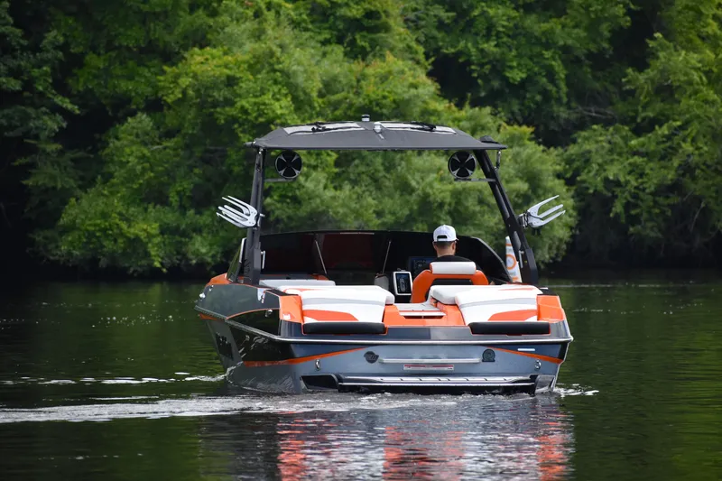 Slide: The Image of 2020 Malibu Wakesetter 22 MXZ on a calm lake, surrounded by lush greenery. - 5