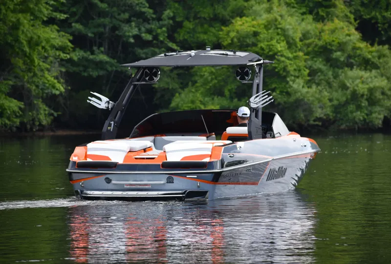 Slide: The Image of 2020 Malibu Wakesetter 22 MXZ boat on a calm lake, surrounded by lush greenery. - 7
