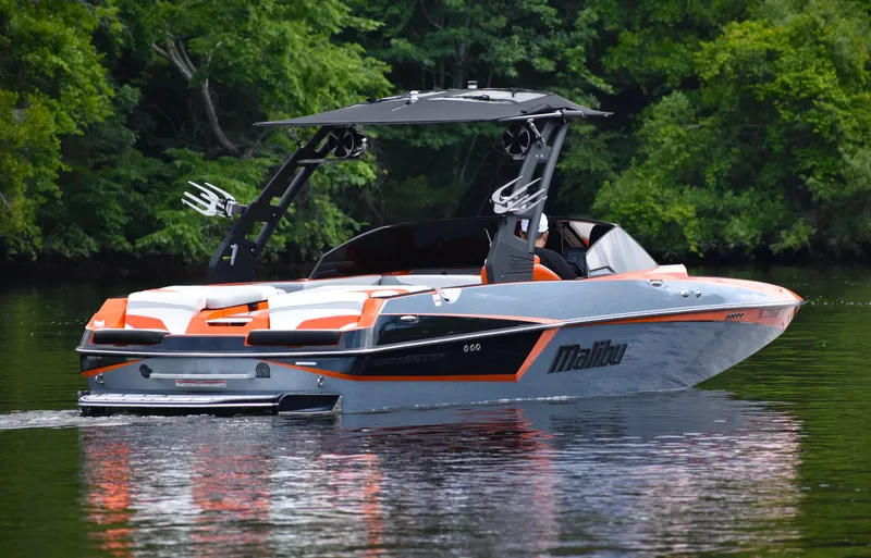 Slide: The Image of 2020 Malibu Wakesetter 22 MXZ boat on calm water, surrounded by lush greenery. - 8
