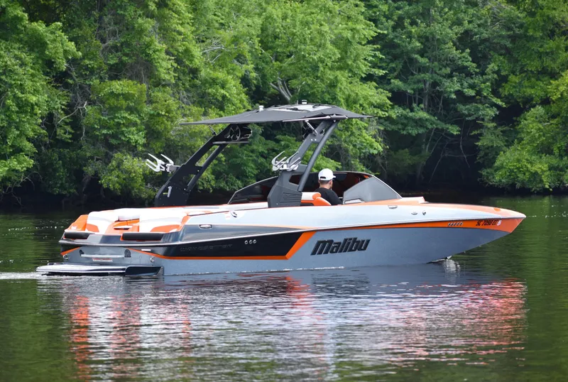 Slide: The Image of 2020 Malibu Wakesetter 22 MXZ boat cruising on a calm lake with lush greenery. - 9