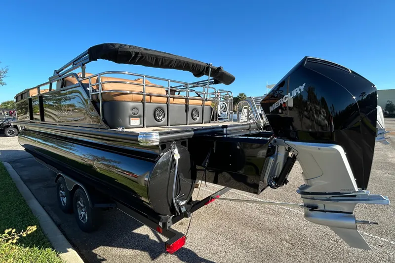 Slide: The Image of 2025 Regency 230 LE3 Sport pontoon boat with Mercury engine, parked outdoors. - 2