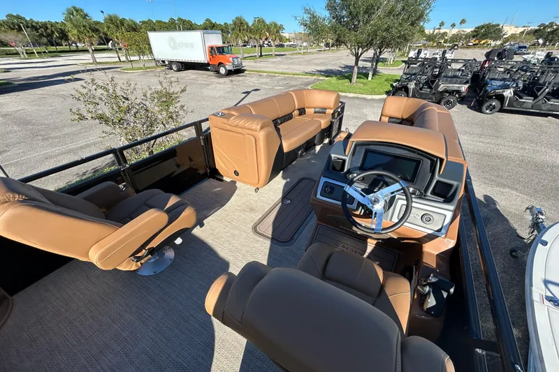 Slide: The Image of 2025 Regency 230 LE3 Sport boat interior with tan seating and modern dashboard. - 6