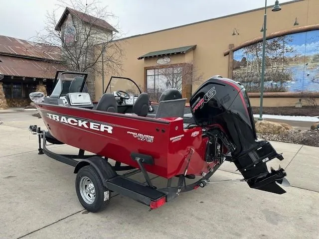 Slide: The Image of 2025 Tracker Pro Guide V-175 Combo boat, red, parked outdoors with powerful outboard motor. - 2