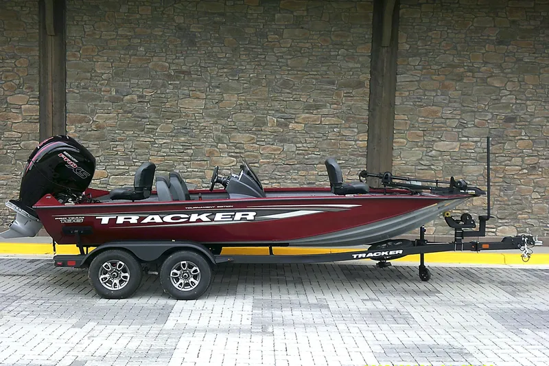 The Image of 2025 Tracker Pro Team 195 Tournament Edition boat on trailer, parked by stone wall. - 0