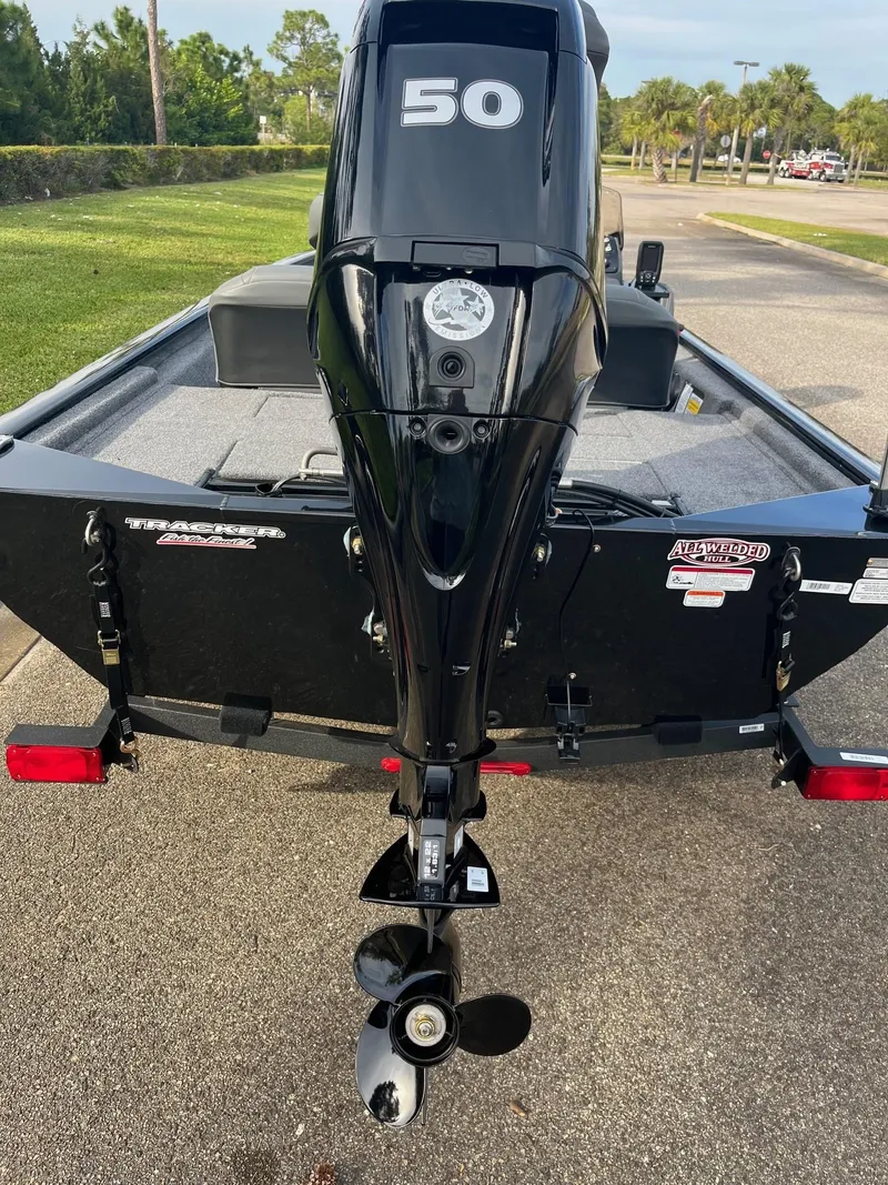 Slide: The Image of 2025 Tracker Pro 170 boat with a 50 HP outboard motor, parked on a sunny day. - 2