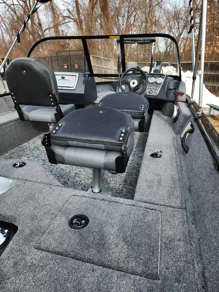 Slide: The Image of 2025 Tracker Pro Guide V-16 WT boat interior with seating and steering console. - 2