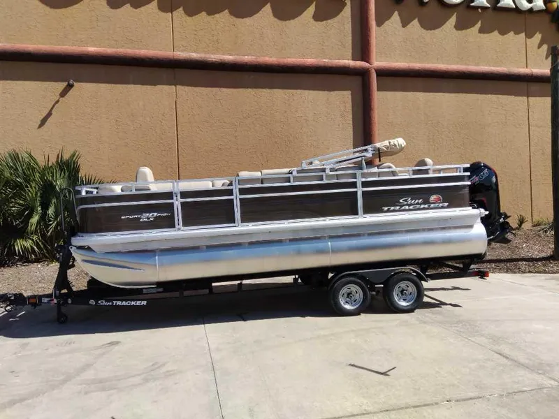 The Image of 2025 Sun Tracker SportFish 20 DLX pontoon boat on trailer, parked outdoors. - 0