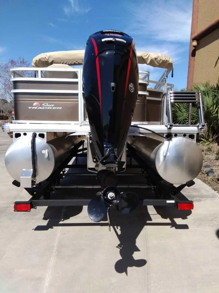 Slide: The Image of 2025 Sun Tracker SportFish 20 DLX pontoon boat, rear view with motor, parked on concrete. - 7