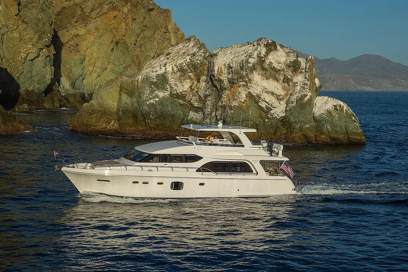 Slide: The Image of 2026 Hampton 650 Pilothouse yacht cruising near rocky coastline. - 20