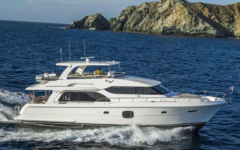 Slide: The Image of 2026 Hampton 650 Pilothouse yacht cruising near rocky coastline. - 28