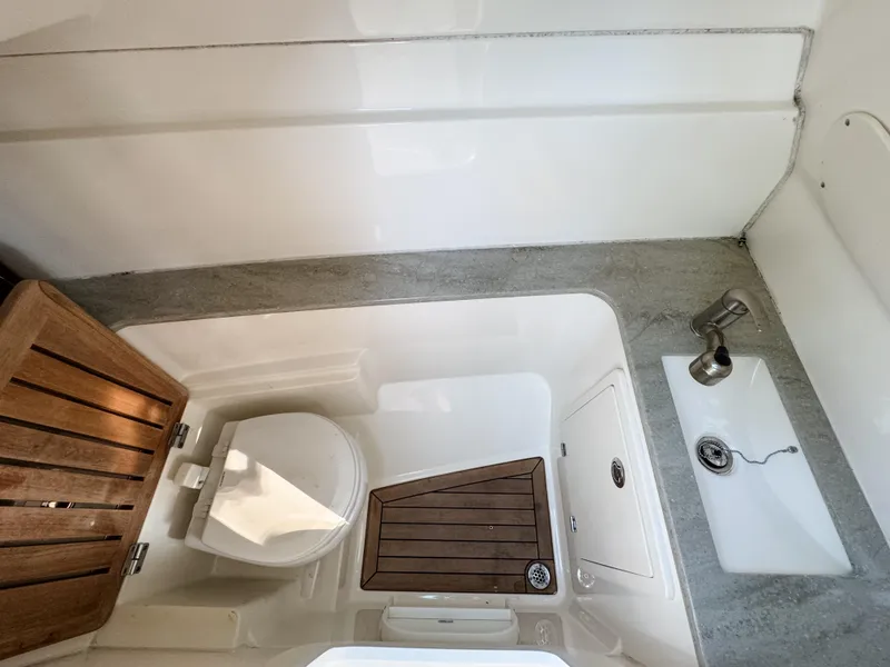 Slide: The Image of 2017 Boston Whaler 320 Vantage boat bathroom with toilet, sink, and wooden accents. - 20
