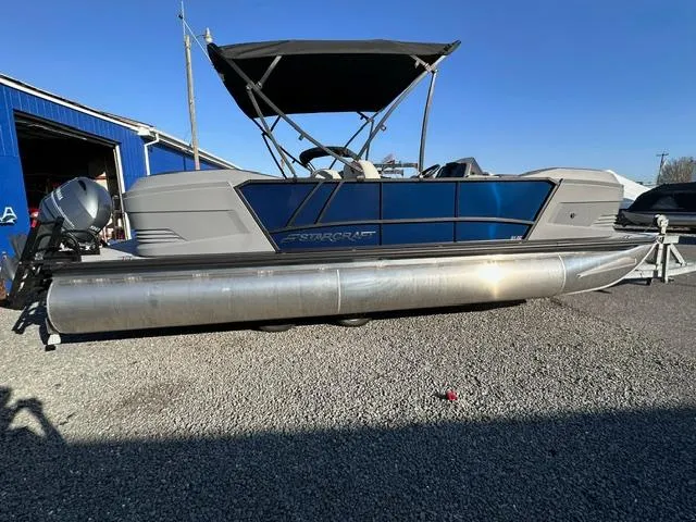 Slide: The Image of 2025 Starcraft GX 22 R DH pontoon boat with canopy, parked on gravel. - 3