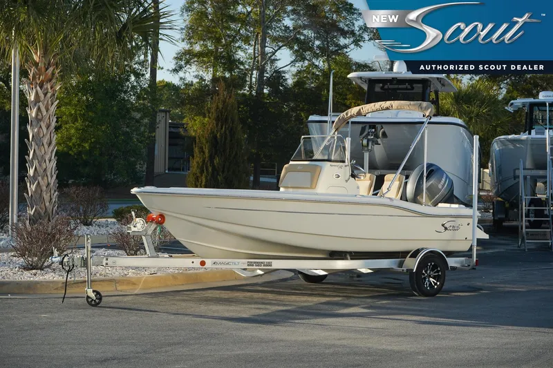 The Image of 2025 Scout 175 Sportfish boat on trailer at authorized dealer, surrounded by trees. - 0