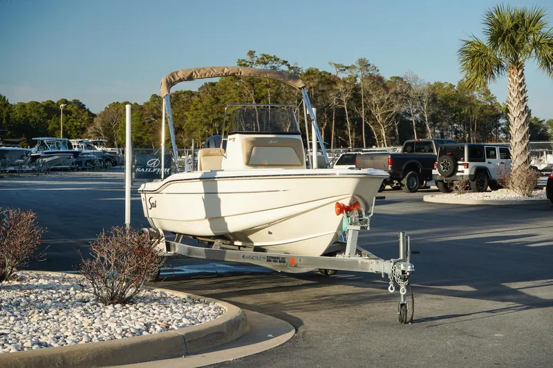 Slide: The Image of 2025 Scout 175 Sportfish boat on trailer in parking lot, surrounded by trees and vehicles. - 3