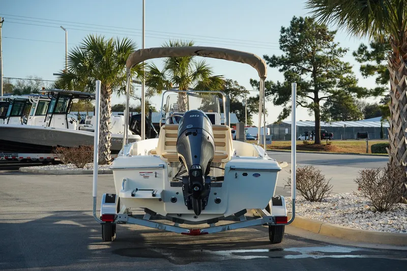 Slide: The Image of 2025 Scout 175 Sportfish boat on trailer, parked outdoors with palm trees in the background. - 6