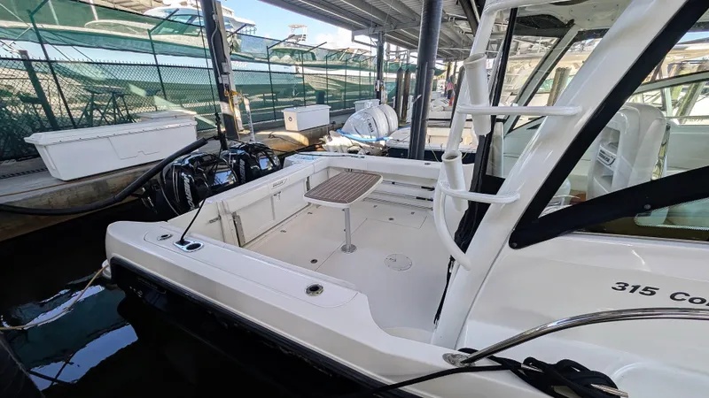 Slide: The Image of 2014 Boston Whaler 315 Conquest docked, showcasing spacious deck and seating area. - 10