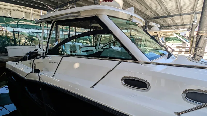 Slide: The Image of 2014 Boston Whaler 315 Conquest boat docked in a covered marina. - 13