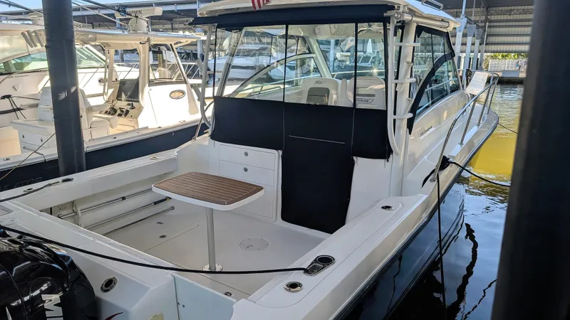 Slide: The Image of 2014 Boston Whaler 315 Conquest boat docked in marina, featuring spacious deck and seating area. - 33