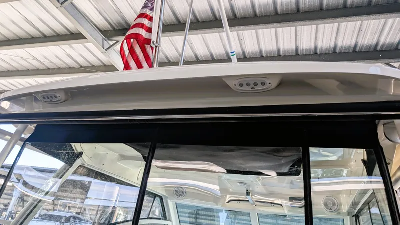 Slide: The Image of 2014 Boston Whaler 315 Conquest boat with American flag under covered dock. - 34