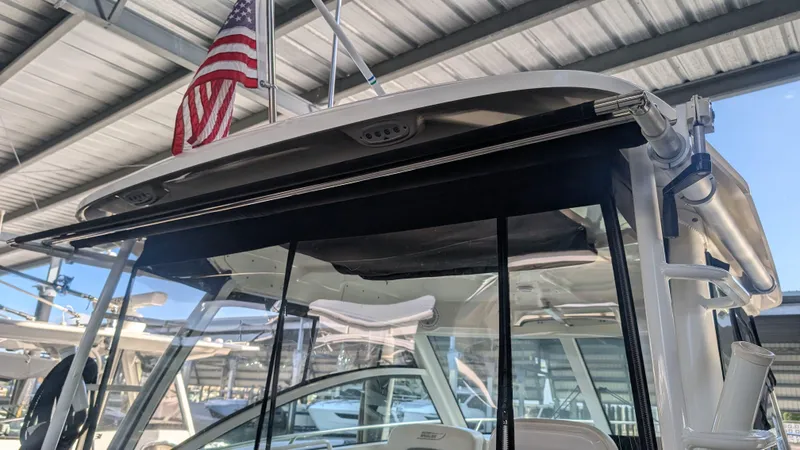 Slide: The Image of 2014 Boston Whaler 315 Conquest boat under a metal roof with American flag. - 35