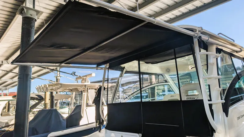 Slide: The Image of 2014 Boston Whaler 315 Conquest with extended canopy under a covered dock. - 36