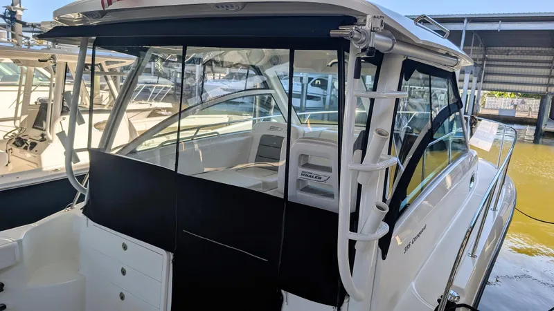 Slide: The Image of 2014 Boston Whaler 315 Conquest boat docked, featuring enclosed cockpit and rod holders. - 37