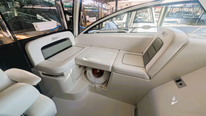 Slide: The Image of 2014 Boston Whaler 315 Conquest interior seating area with white upholstery and storage compartment. - 40