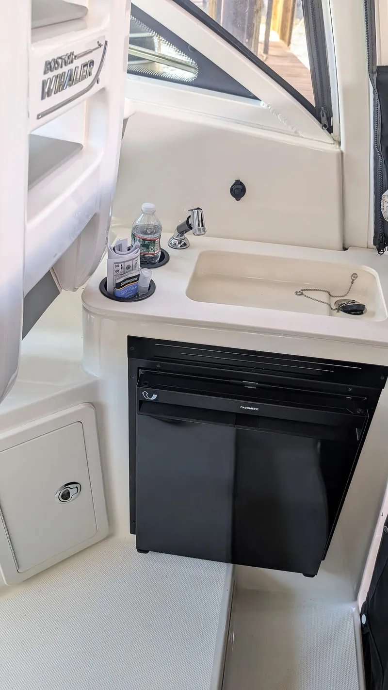 Slide: The Image of 2014 Boston Whaler 315 Conquest interior with sink, mini fridge, and storage. - 46