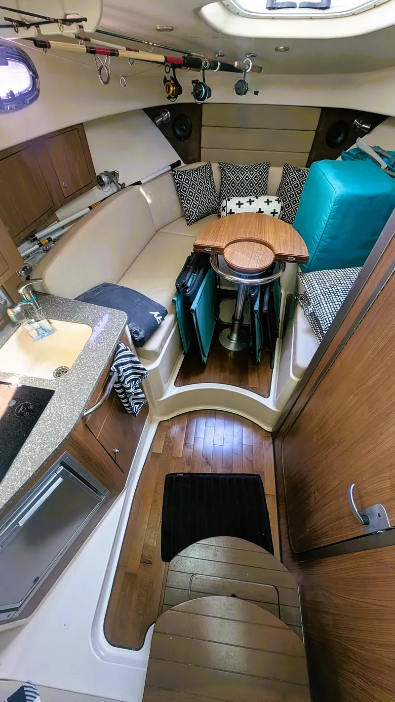 Slide: The Image of Interior of 2014 Boston Whaler 315 Conquest, featuring cozy seating and compact kitchen area. - 48