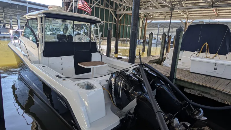 Slide: The Image of 2014 Boston Whaler 315 Conquest docked in a marina, featuring dual outboard engines. - 6