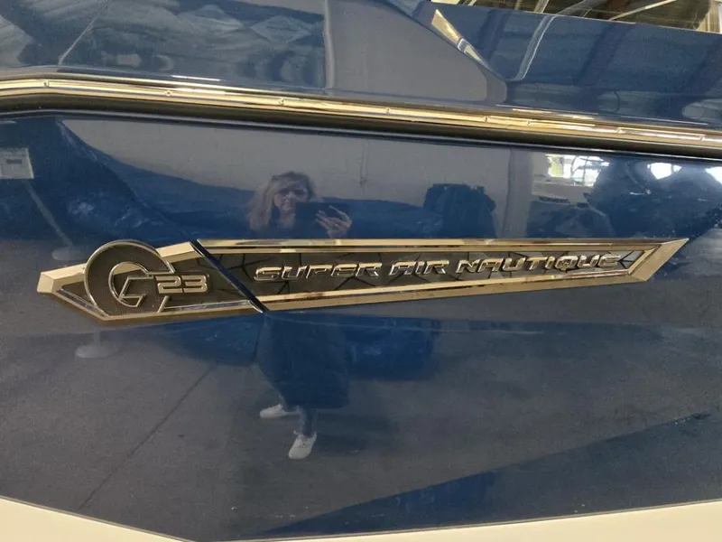 Slide: The Image of 2025 Nautique Super Air Nautique G23 boat emblem on blue hull. - 18