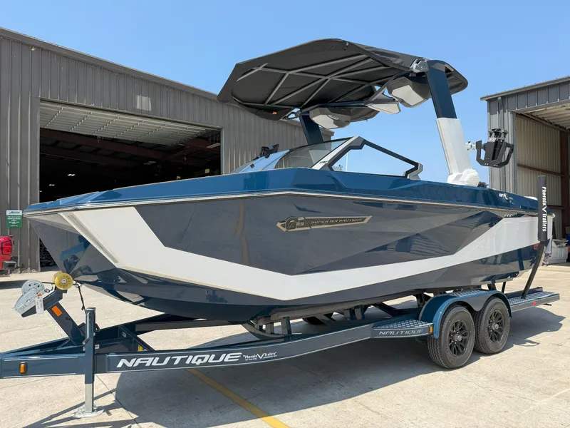Slide: The Image of 2025 Nautique Super Air Nautique G23 boat on trailer, parked outside a warehouse. - 43