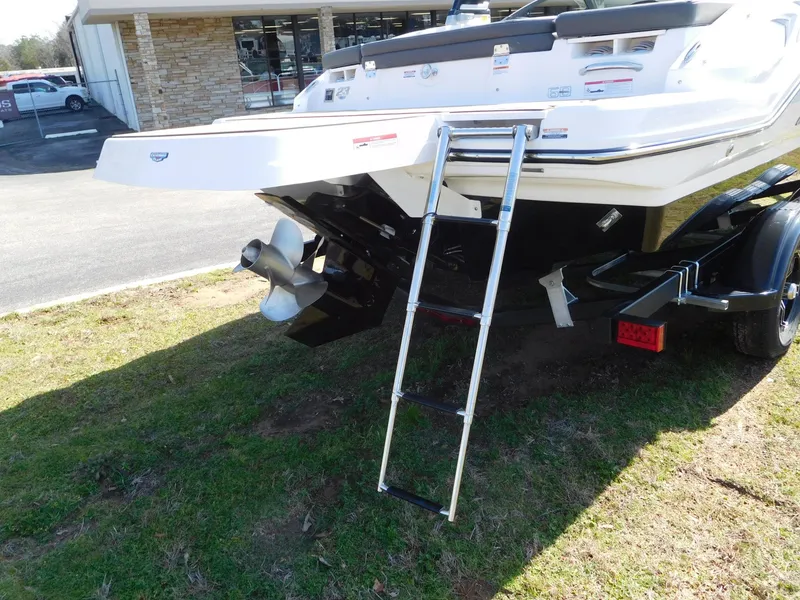Slide: The Image of 2025 Chaparral 23 SSi boat with ladder and propeller, parked on grass. - 13