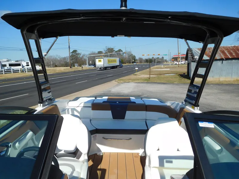 Slide: The Image of 2025 Chaparral 23 SSi boat interior with seating, parked near a road. - 4