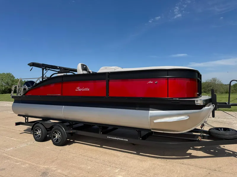 Slide: The Image of 2025 Barletta ARIA 22UC pontoon boat on trailer, red and black design, sunny day. - 15