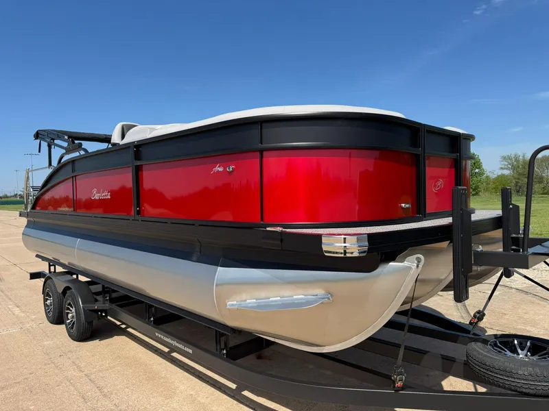 Slide: The Image of 2025 Barletta ARIA 22UC pontoon boat with red and black exterior on a trailer. - 16
