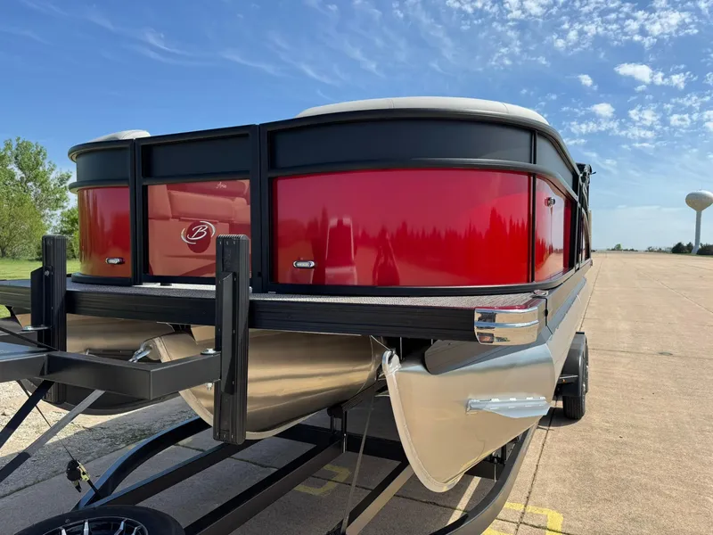 Slide: The Image of 2025 Barletta ARIA 22UC pontoon boat with red exterior on a trailer under a blue sky. - 5